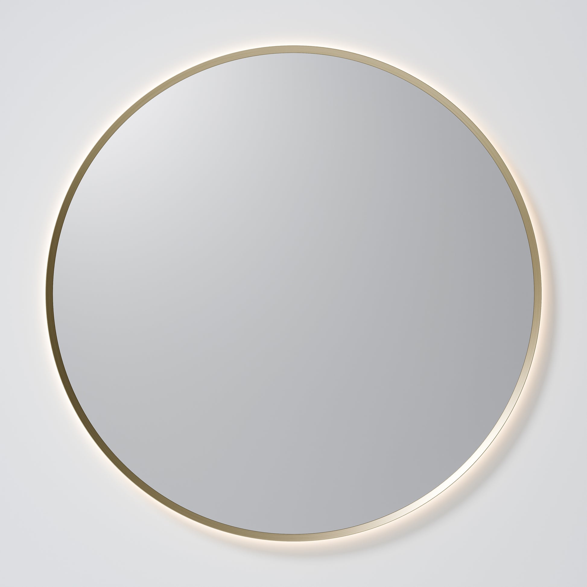 Round mirror with a gold frame on a white wall