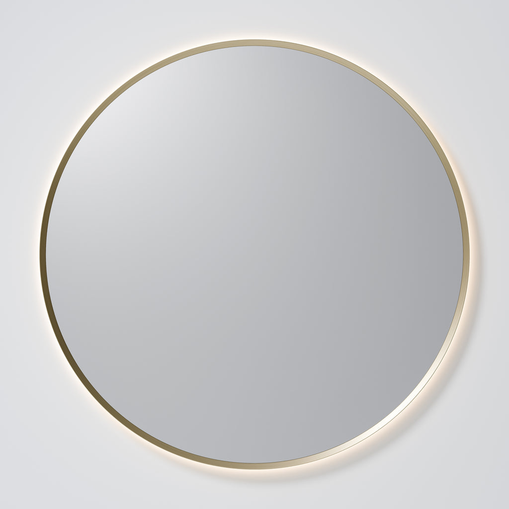 Round mirror with a gold frame on a white wall